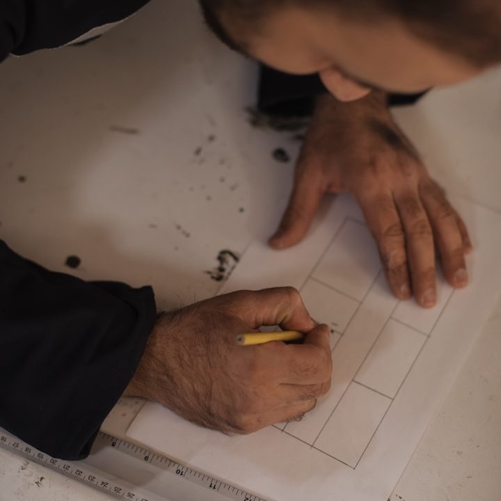 Eine Person zeichnet mit einem Bleistift auf Papier, um ein Layout zu erstellen.